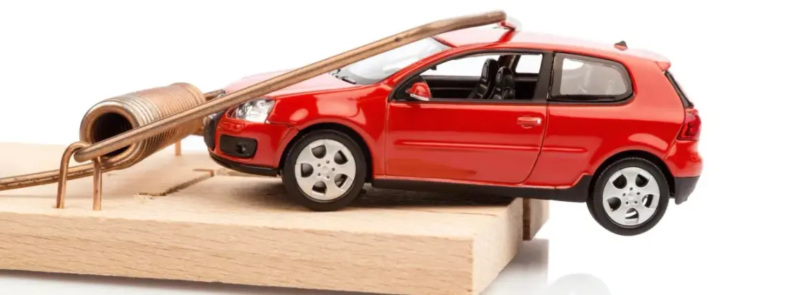 Une petite voiture rouge est piégée sur une souricière. Attention, voici comment acheter une voiture d'occasion sans tomber dans le piège !