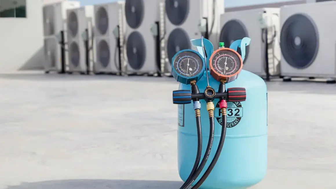 Bouteille de gaz R32 pour climatisation de voiture, avec manomètres, devant des unités extérieures de climatisation.