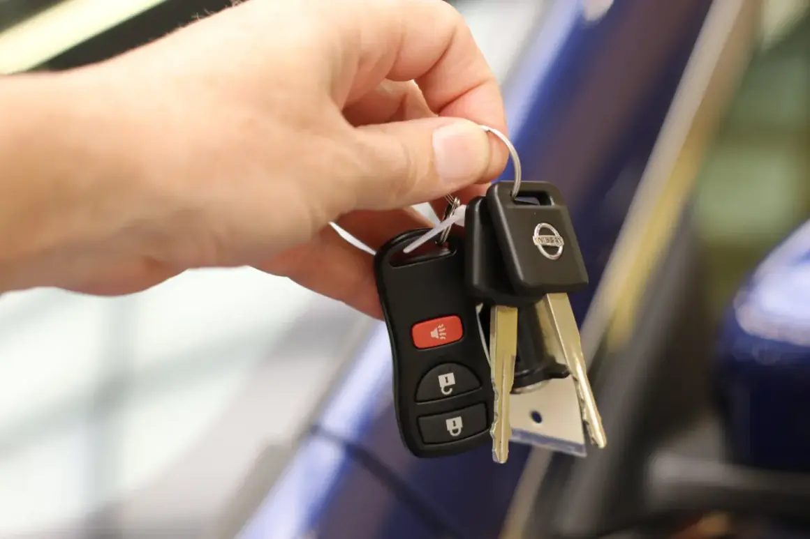 Une main tient les clés d'une voiture Nissan, symbolisant la signature d'un contrat de location voiture.