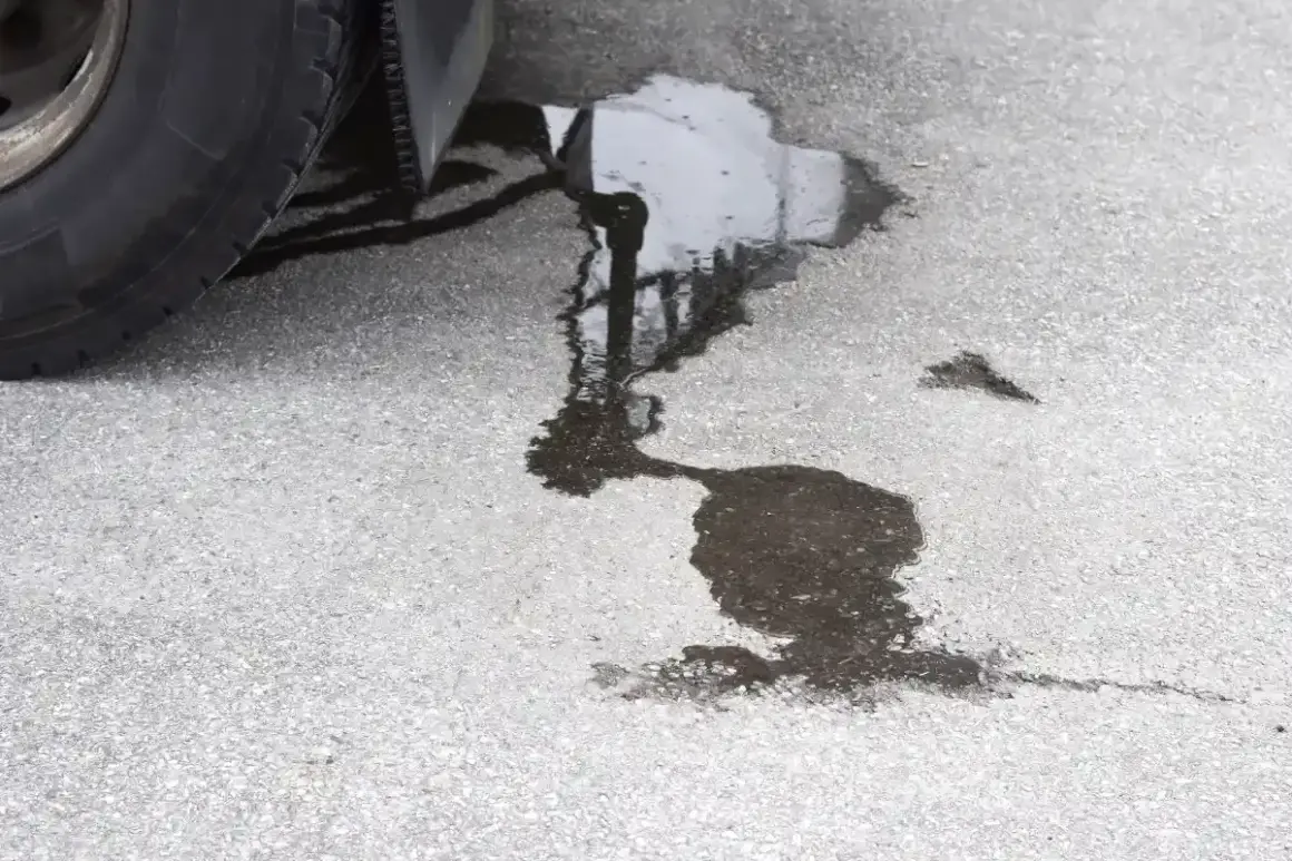 Une flaque sombre sur le bitume, près d'un pneu, suggère une fuite liquide de frein.