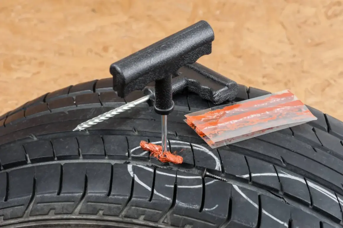 Kit de réparation pour pneu de voiture : un outil insère une mèche dans un pneu crevé, prêt à réparer.