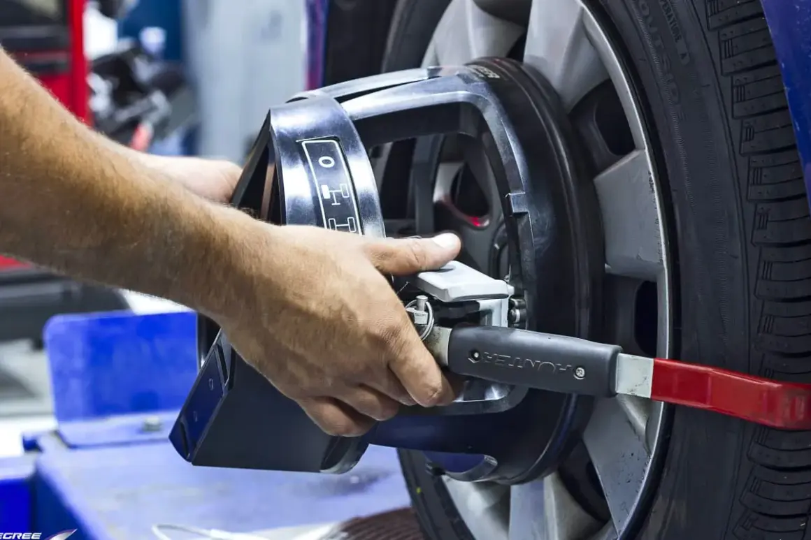 Mains ajustant un appareil sur une roue pour l'équilibrage pneu et parallélisme.
