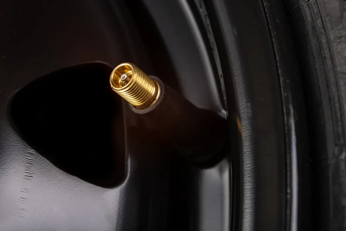 Gros plan sur une valve de pneu dorée, prête à changer.