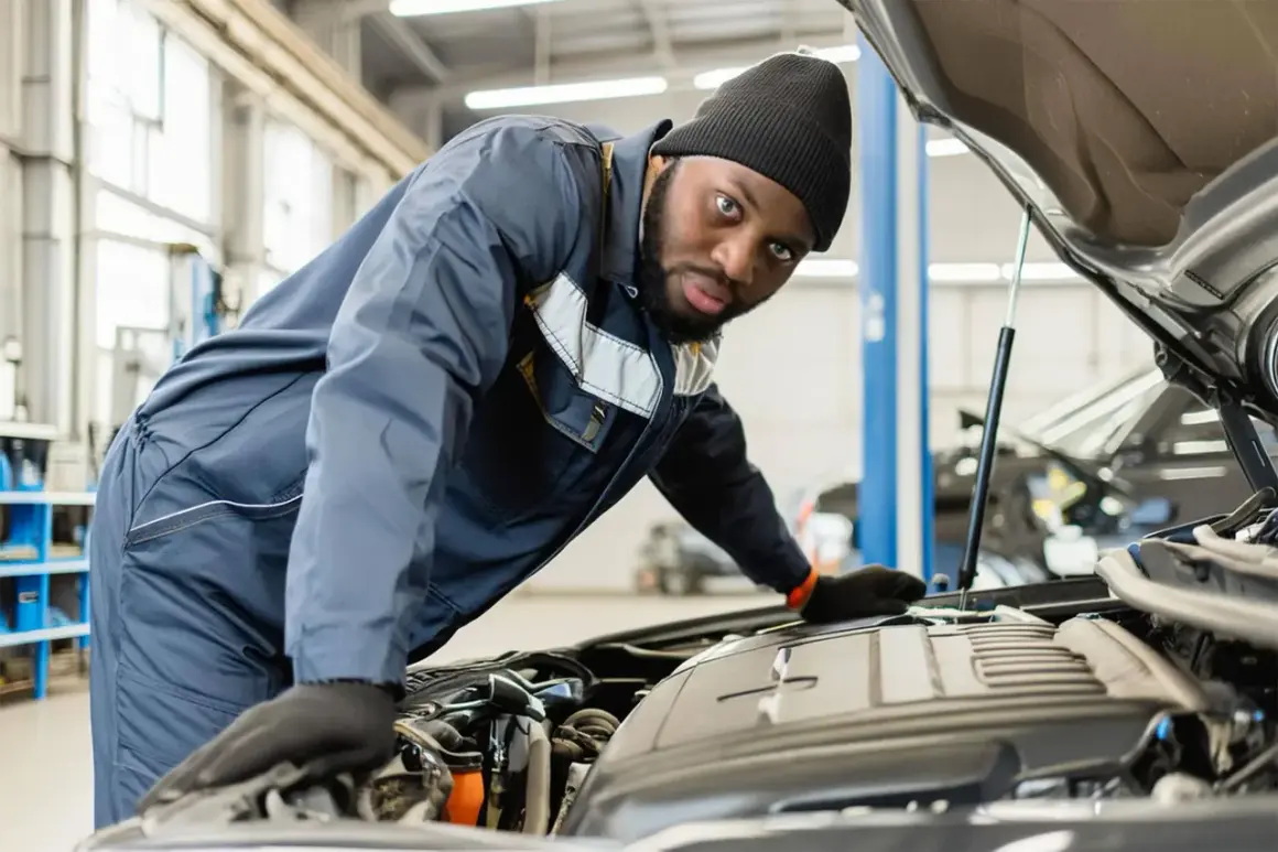 Mécanicien concentré sur le moteur d'une voiture. Il vérifie le niveau d'huile, une étape clé pour savoir combien de temps dure une vidange.