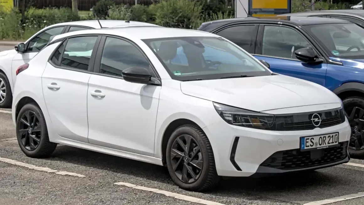 Une Opel Corsa blanche, prête à démarrer avec son moteur efficace, se gare à côté d'autres véhicules.