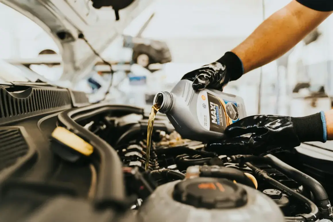 Main d'un mécanicien versant de l'huile neuve dans le moteur d'une voiture diesel. L'entretien régulier est essentiel pour la vidange de votre voiture diesel.