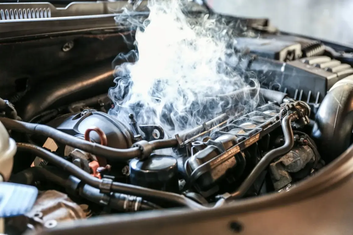 Fumée épaisse s'échappe d'un moteur de voiture, suggérant un bruit de cliquetis moteur diesel inquiétant.