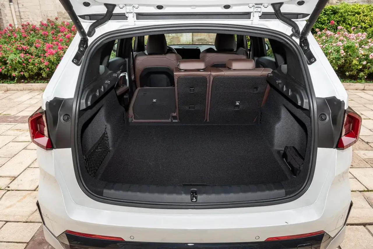 Vue arrière du coffre d'une BMW X1, sièges rabattus pour un essai. Espace de chargement spacieux.
