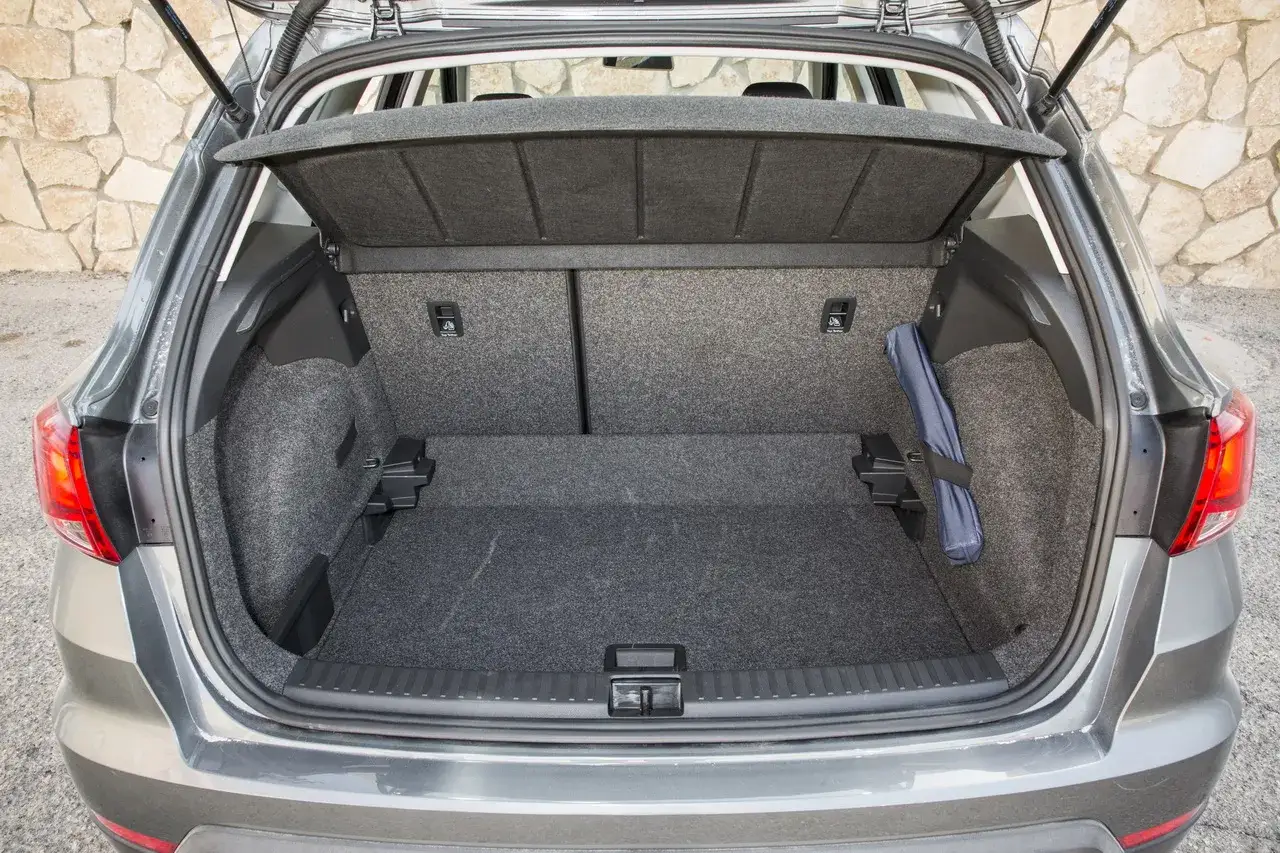 Coffre ouvert d'une Seat Arona grise. Un kit de sécurité bleu est rangé sur le côté. Avis sur l'espace de chargement.