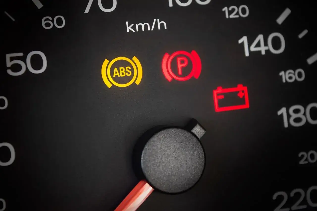 Tableau de bord avec voyant ABS allumé, symptôme d'un capteur ABS défectueux. Voyant de frein à main et de batterie également allumés.