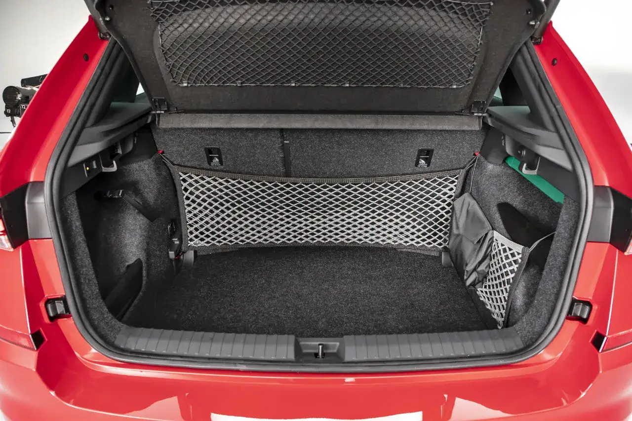Coffre ouvert d'une Skoda Kamiq rouge, montrant son espace de rangement avec filets. Les Skoda Kamiq dimensions sont idéales pour le quotidien.