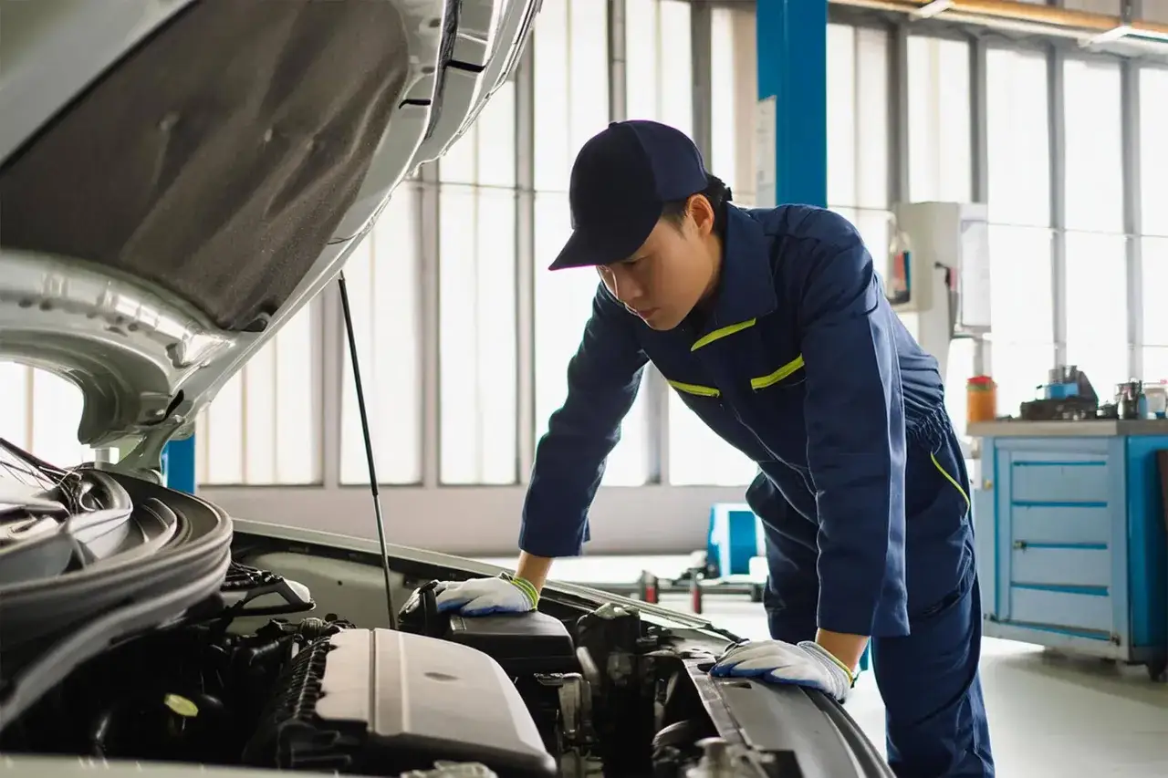 Mécanicien en bleu de travail examinant un moteur de voiture. Il est temps de vérifier le tarif entretien mini pour votre véhicule.