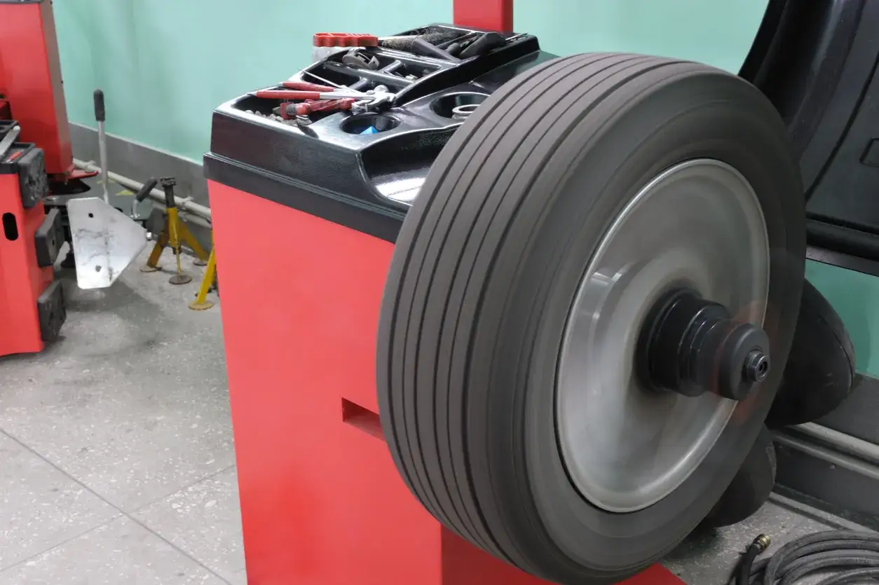 Machine d'équilibrage de pneu en action, outil essentiel pour l'équilibrage pneu et parallélisme.