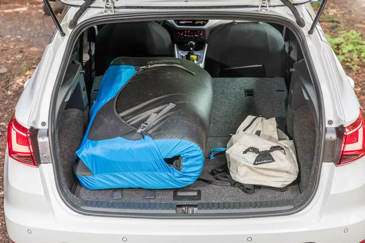 Le coffre d'une Seat Arona est chargé d'un grand sac de couchage bleu et noir et d'un sac à dos beige, prêt pour une aventure.