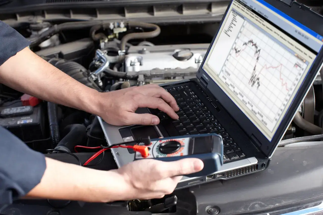 Un mécanicien utilise un ordinateur portable et un multimètre pour diagnostiquer un problème moteur. Peut-on rouler avec un calculateur HS ? Ce diagnostic est essentiel.