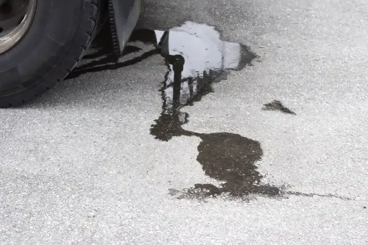 Une flaque sombre sur l'asphalte, près d'un pneu, indique une fuite liquide de frein.