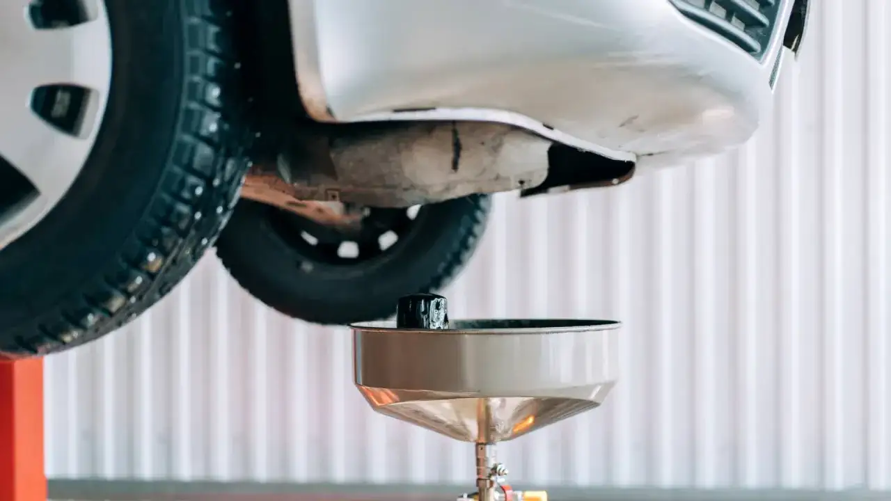 Vidange boîte de vitesse manuelle : un filtre à huile usagé est prêt à être retiré sous une voiture soulevée.
