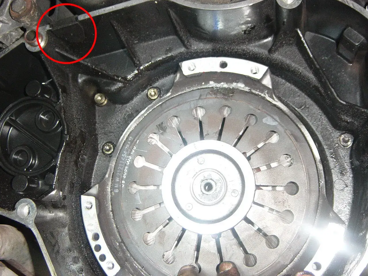 Zone rouge sur une fuite de joint spi, près du volant moteur et de la cloche d'embrayage.