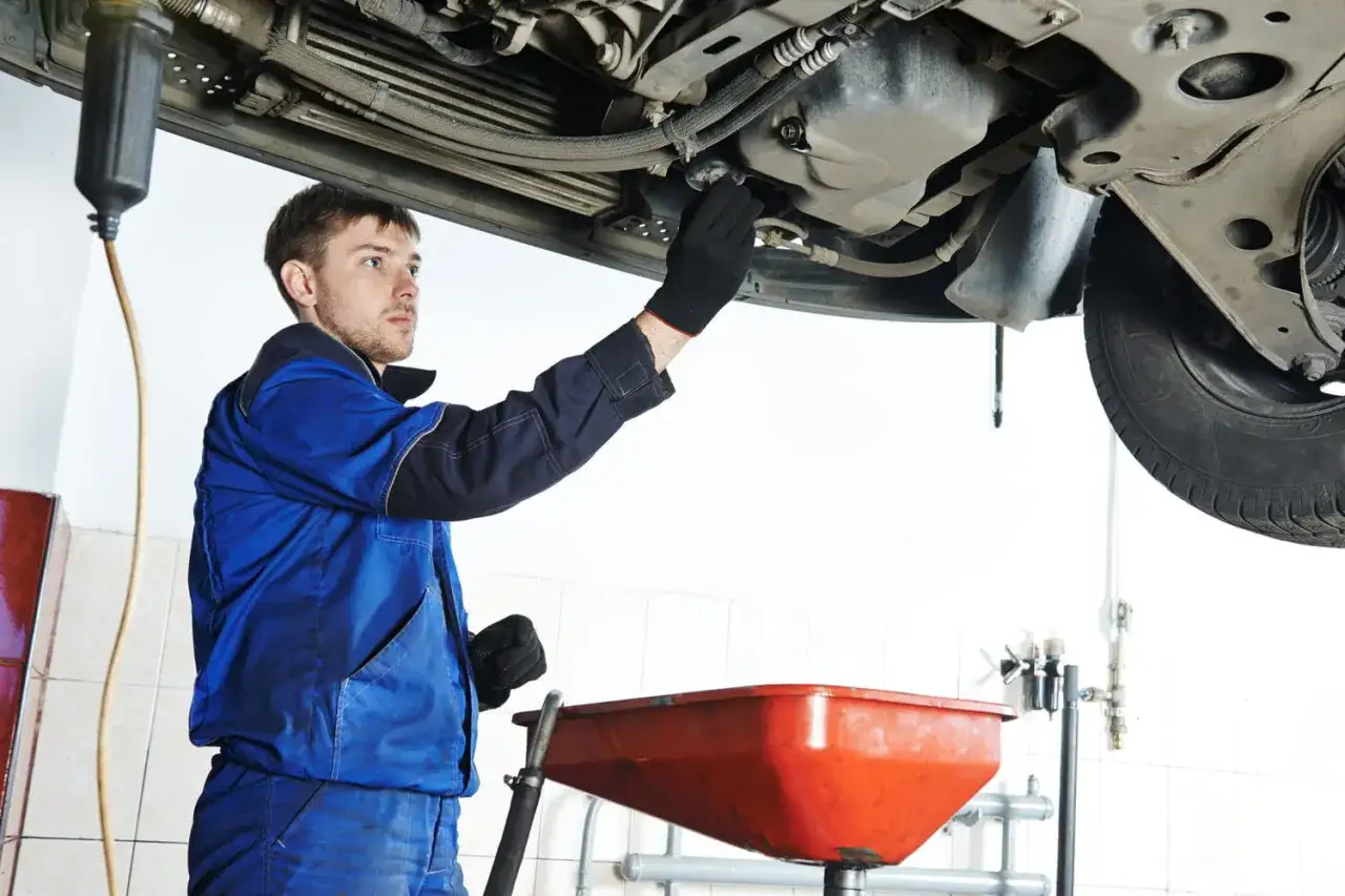 Mécanicien effectuant la vidange d'une voiture essence. Le prix de la vidange est abordable pour ce service essentiel.