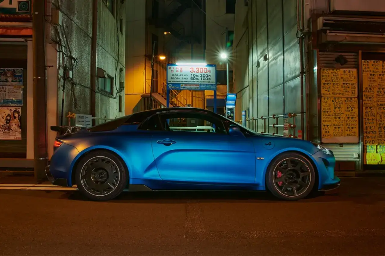 Alpine A110 bleue, prête à atteindre sa vitesse max dans une ruelle japonaise illuminée.