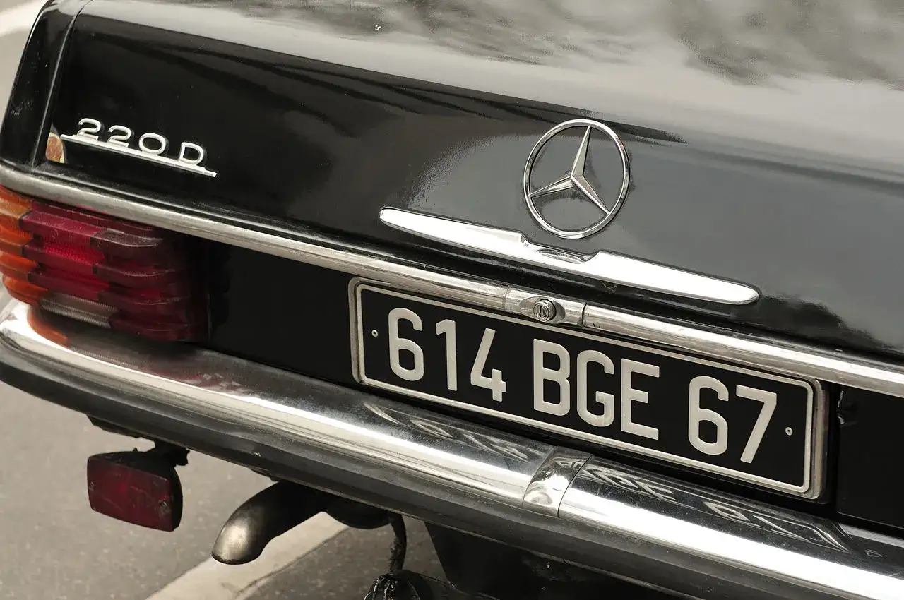 Arrière d'une Mercedes 220D noire avec plaque d'immatriculation