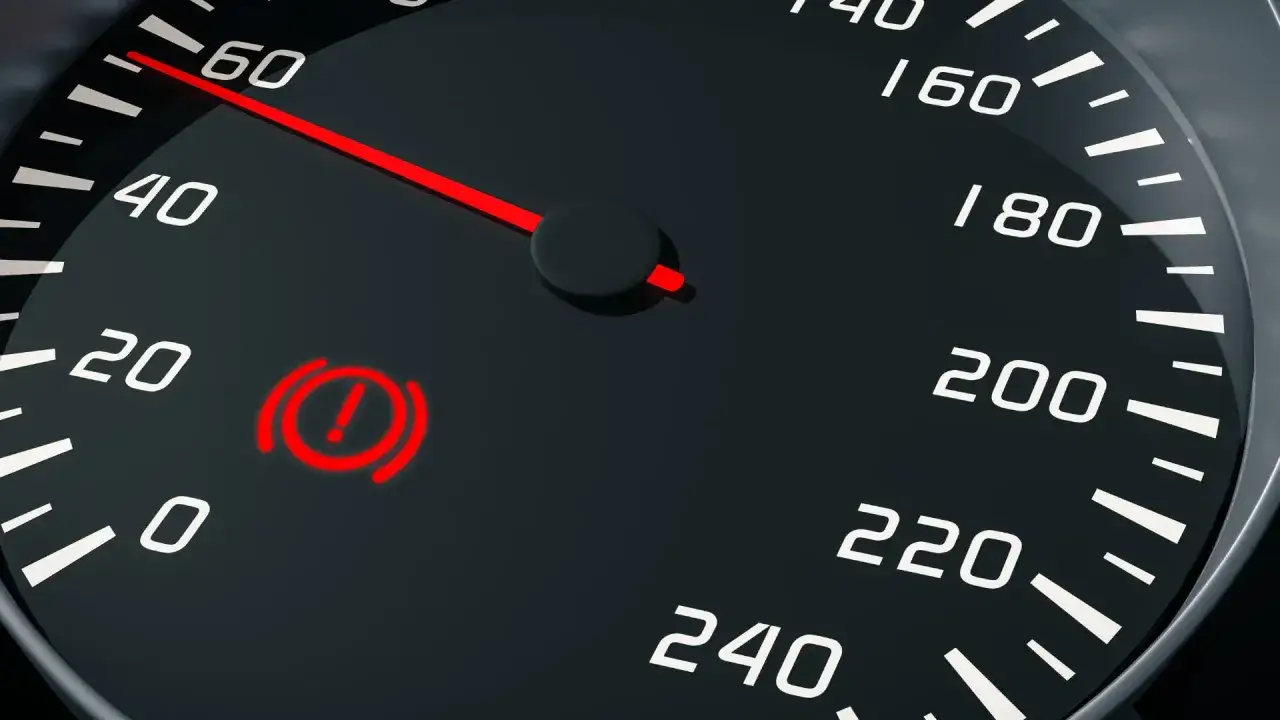 Tableau de bord d'une voiture avec le voyant rouge d'une panne du syst&egrave;me de freinage allum&eacute;. L'aiguille du compteur de vitesse indique environ 60.