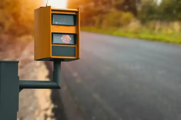 Radar de vitesse orange sur le bord de la route, rappelant de ne pas utiliser le téléphone au volant.