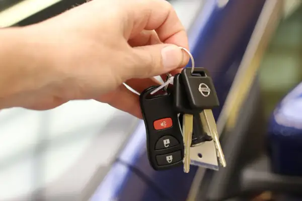 Une main tient les clés d'une voiture Nissan, symbolisant la signature d'un contrat de location voiture.