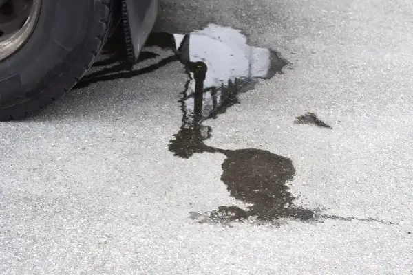 Une flaque sombre sur le bitume, près d'un pneu, suggère une fuite liquide de frein.