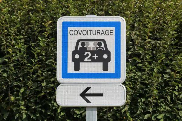Panneau de signalisation "Covoiturage" indiquant une voie réservée aux véhicules de 2 personnes ou plus. Une flèche noire pointe vers la gauche.