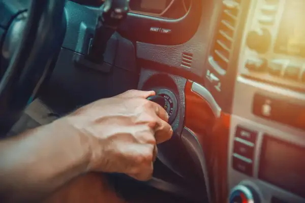 Main d'un conducteur tournant la clé de contact, espérant que la voiture cale en roulant ne se reproduise pas.