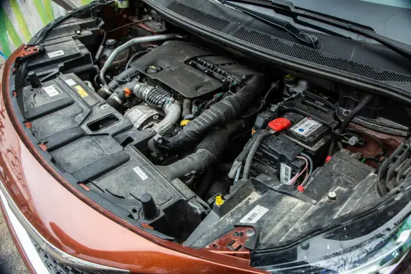 Vue détaillée du compartiment moteur d'une voiture diesel, prêt pour un entretien. On y voit le bloc moteur, la batterie et divers composants.