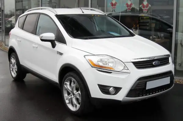 Un Ford Kuga blanc, symbole de fiabilité, garé devant un showroom.