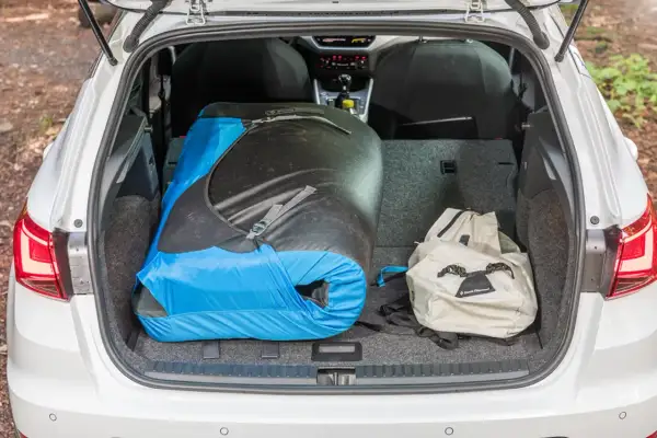 Le coffre d'une Seat Arona est chargé d'un grand sac de couchage bleu et noir et d'un sac à dos beige, prêt pour une aventure.
